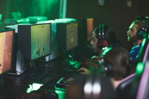 Young men in headsets for online communication sitting in row and participating in cyber game